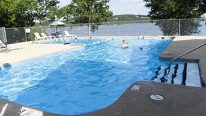Una piscina con sillas de descanso y vistas al lago.