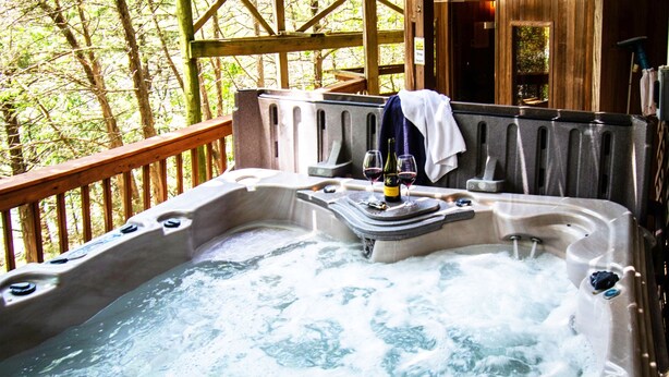 Un jacuzzi con cubierta de madera y vista a los árboles.
