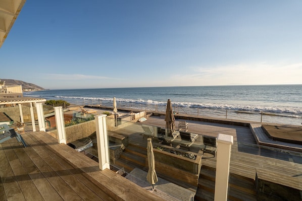 A wooden deck with outdoor seating and a view of the ocean.