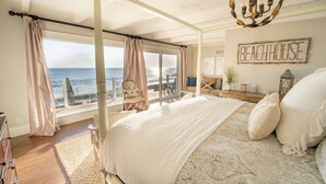 Et soveværelse med en stor seng, havudsigt og et skilt med teksten "BEACHHOUSE".