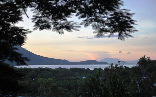 A coastal landscape with a mountain in the background, dense greenery in the foreground, and a clear sky. - The Sanctuary Retreat (Trinity Beach)