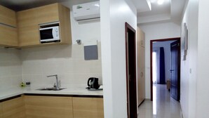 A modern kitchen with wooden cabinets, a built-in microwave, and a coffee machine. - Résidence Ethan (Abidjan)