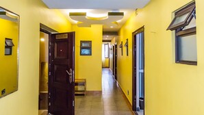 A hallway with yellow walls, a tiled floor, and a door leading to a room. - Hotel Green Court Nairobi (Nairobi)