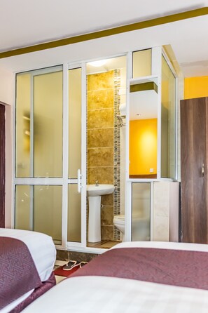 A hotel room with a bed, a bathroom with a shower, and a toilet. - Hotel Green Court Nairobi (Nairobi)