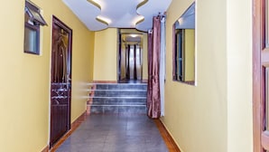 A hallway with a wooden door, a window, and a staircase leading to another room. - Hotel Green Court Nairobi (Nairobi)