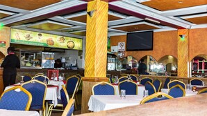A restaurant with blue upholstered chairs, white tablecloths, and a menu board advertising 'Refreshing African style' dishes. - Hotel Green Court Nairobi (Nairobi)