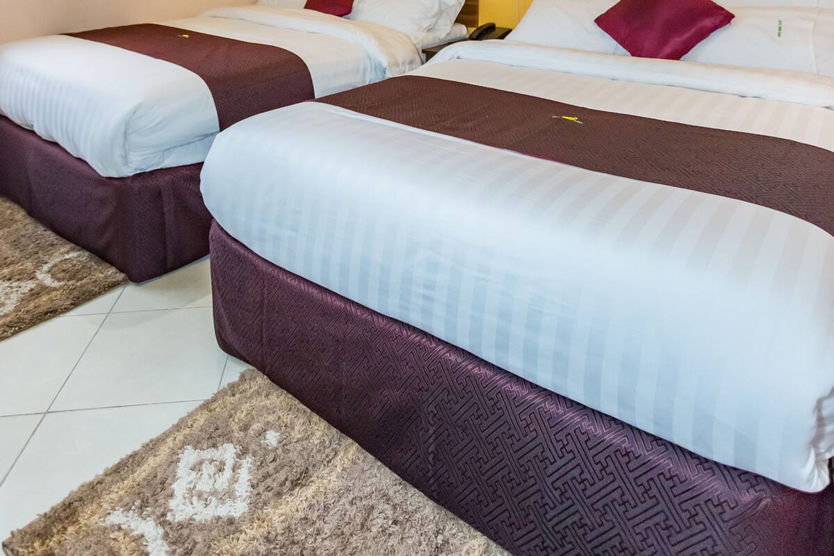 A hotel room with two beds, a wooden headboard, and a yellow accent wall.