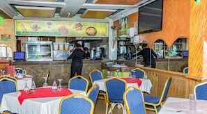 A restaurant with a counter displaying food options and a seating area with tables and chairs. - Hotel Green Court Nairobi (Nairobi)