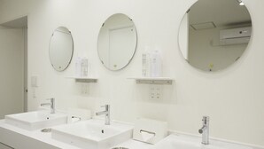 A modern bathroom with three sinks, each with a mirror above. There are shelves with toiletries and a towel dispenser. - IN FRAME HOSTEL enoshima - Hostel (Fujisawa)