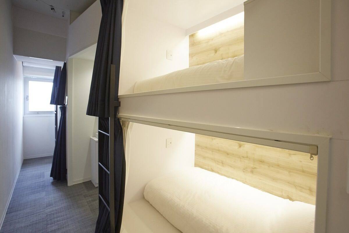 A bunk bed room with a wooden headboard, a window with curtains, and a carpeted floor.