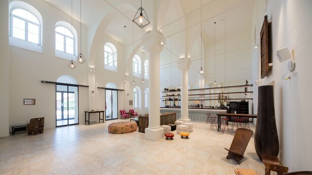 A spacious interior with high ceilings, arched windows, and a central seating area with ottomans. - Gabrium (Maria Enzersdorf)