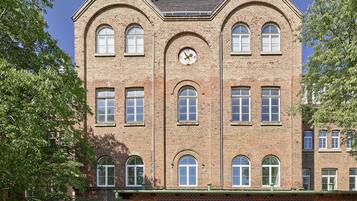 Un edificio in mattoni di più piani, con ampie finestre e un orologio sulla facciata.