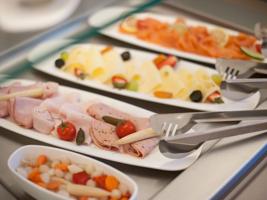 A buffet with various food options including sliced meats, cheeses, and vegetables.
