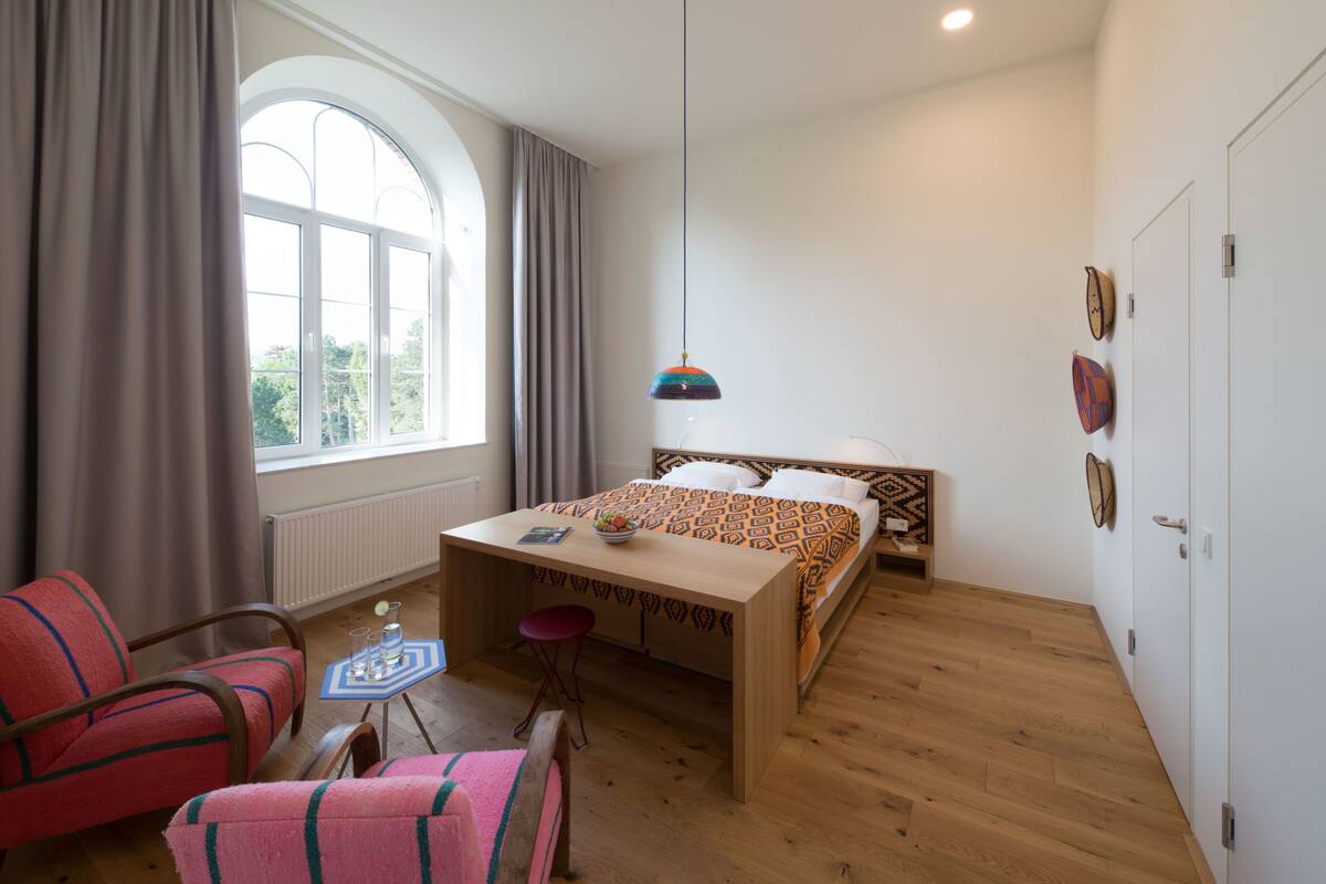 Un dormitorio con cama, escritorio, silla, mesa y ventana.