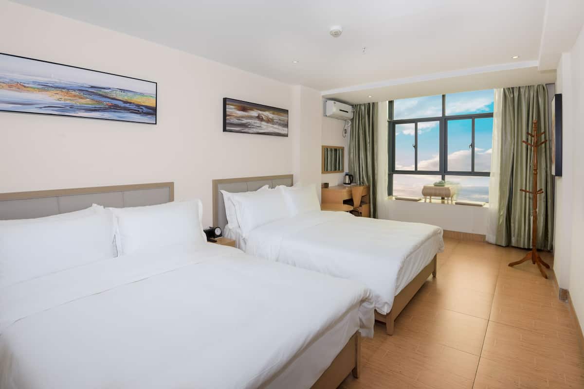 Une chambre d’hôtel avec deux lits, une grande fenêtre donnant sur un beau paysage et un appareil de climatisation fixé au plafond.