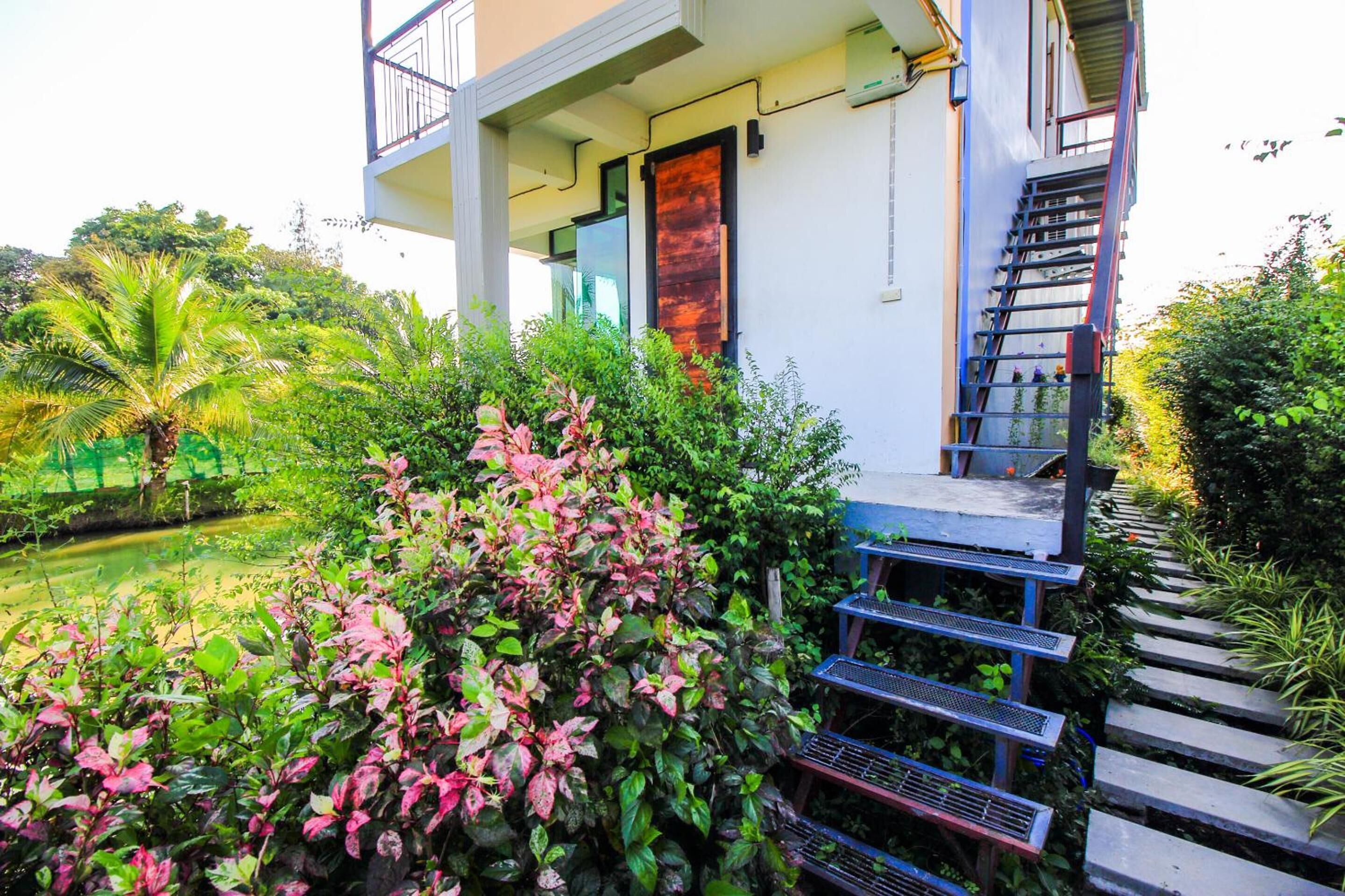 A modern building with a balcony, a staircase, and lush greenery.
