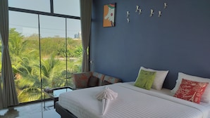 A modern hotel room with a large bed, a view of palm trees, and a blue wall. - Plern Salaya Resort (Phutthamonthon)
