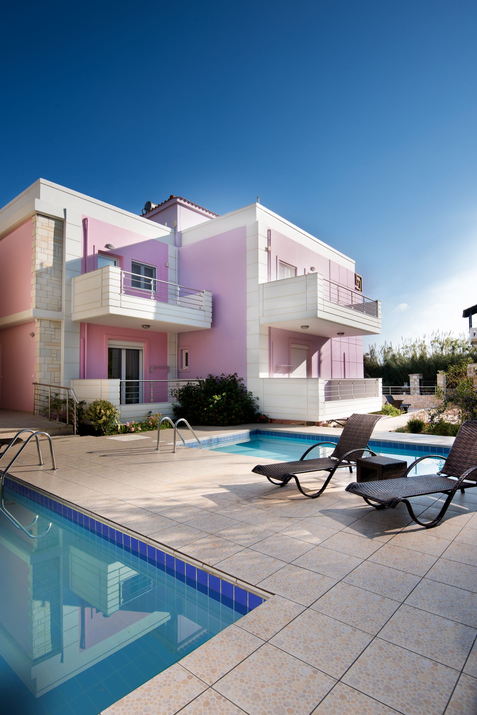 A two-story building with a pool and lounge chairs.