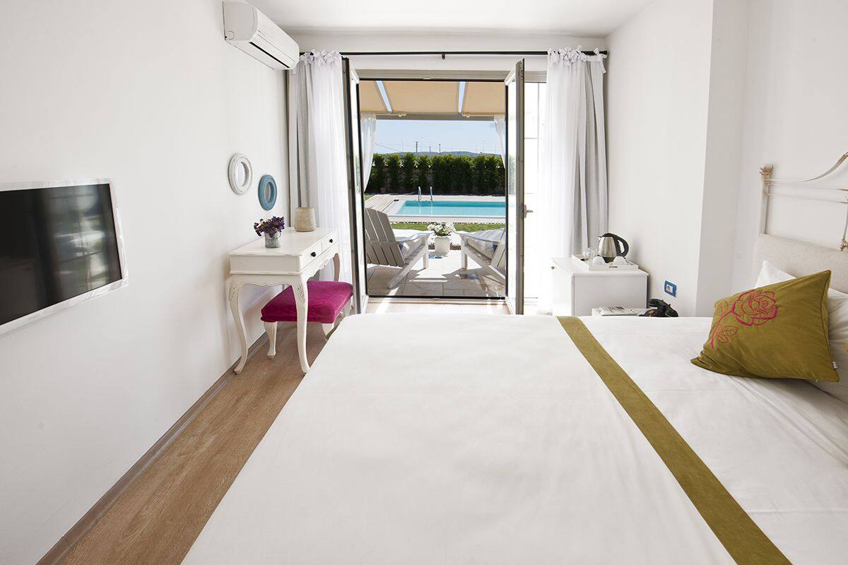 A hotel room with a bed, a desk, a chair, and a view of a pool.