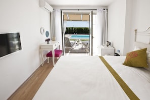 Ein Hotelzimmer mit Bett, Schreibtisch, Stuhl und Blick auf einen Pool.