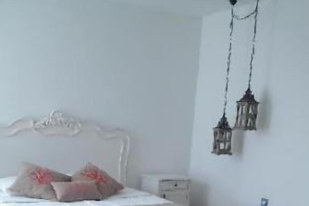A bedroom with a bed, bedside table, and a chair.