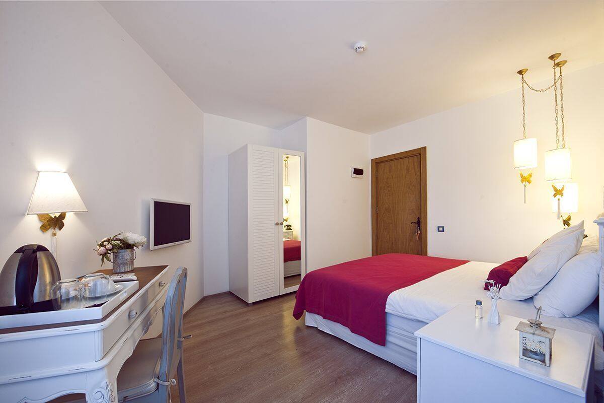 A hotel room with a bed, a desk, a chair, a TV, a wardrobe, and a door.