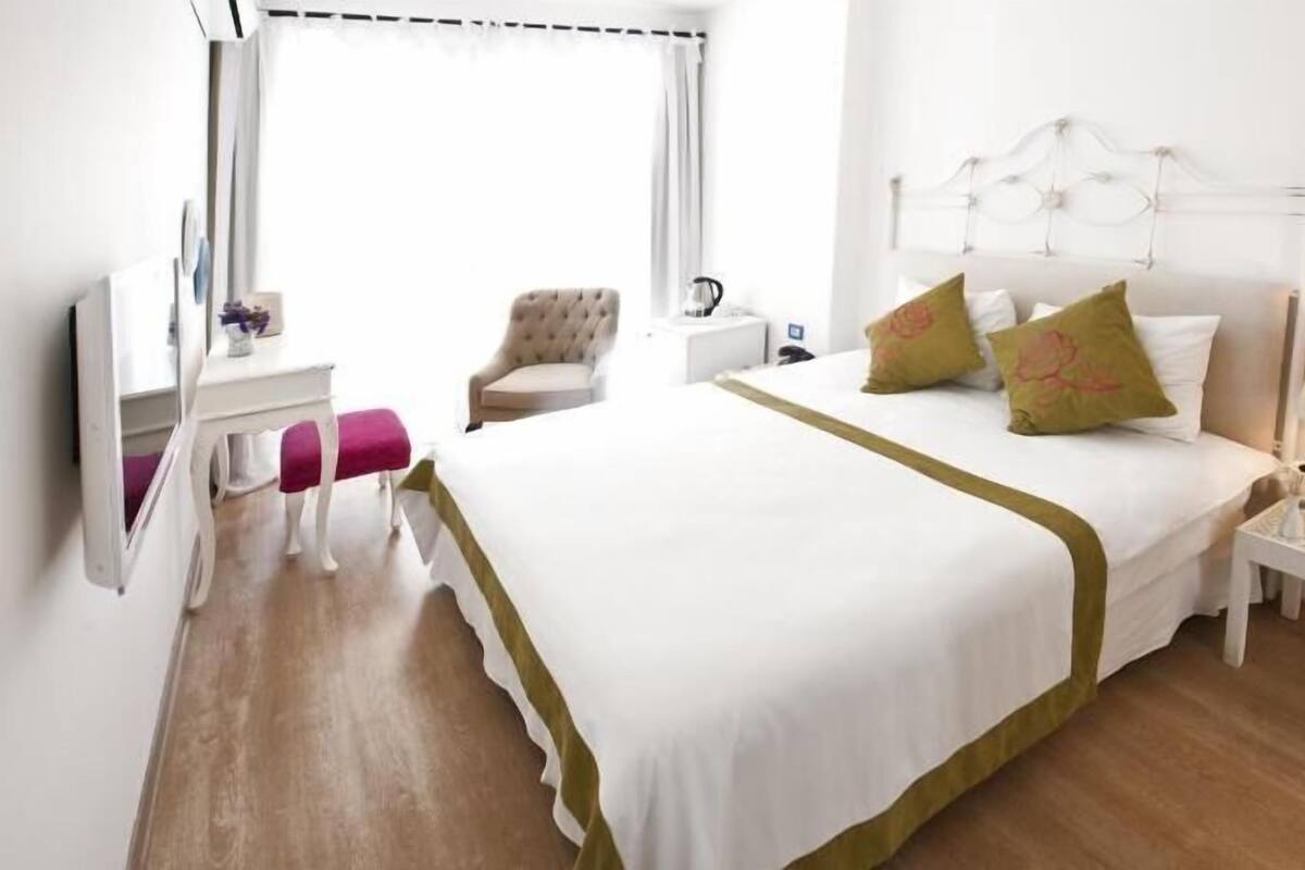 A hotel room with a bed, a chair, a desk, a lamp, and a nightstand.