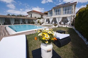 Ein Poolbereich mit großem Pool, Liegestühlen und einer Blumenanordnung.