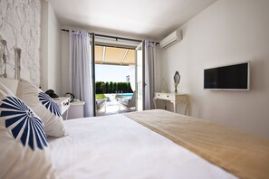 Ein Schlafzimmer mit Bett, Schreibtisch, Fernseher und Blick auf ein Außenbecken.