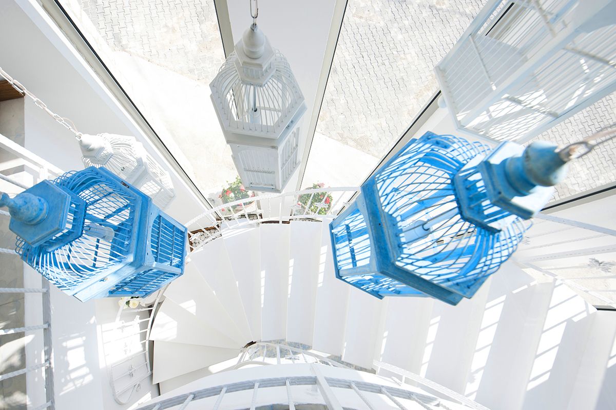 Una habitación blanca con techo circular y faroles azules y blancos colgando.