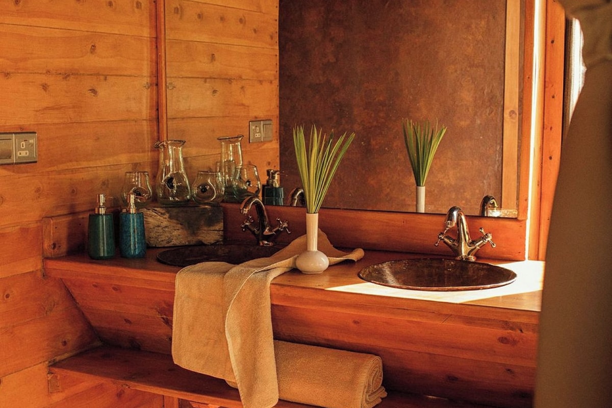 A wooden cabin bathroom with a sink, mirror, and towel rack.