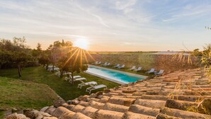 Zona de piscina con sillones de descanso y un muro de piedra.