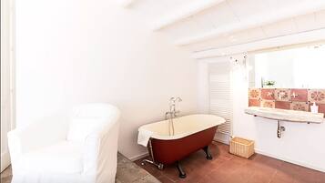 Bathroom features a bathtub, a chair, and a wicker basket.