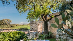 Un área de comedor al aire libre con un muro de piedra, una mesa de madera y sillas.