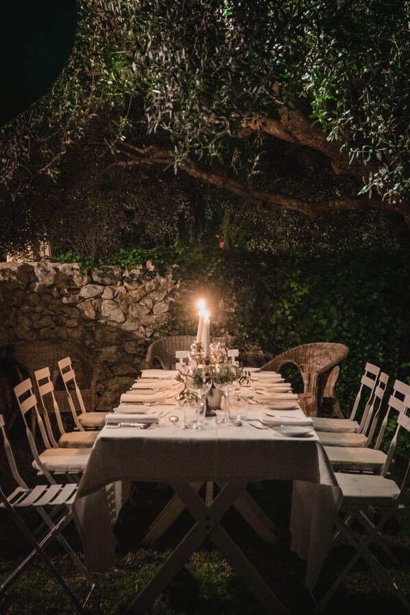 An outdoor dining area with a stone wall backdrop, a table set for four, and chairs. - Baglio Occhipinti (Vittoria)