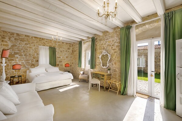 Una habitación con pared de piedra, una cama, un escritorio y una silla.