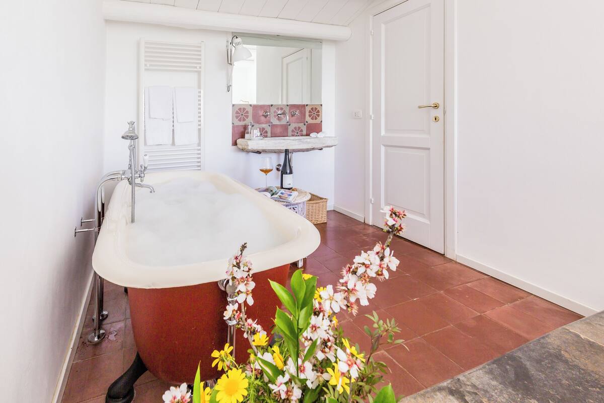 A bathroom with a freestanding bathtub, a sink with a decorative tile backsplash, and a mirror above the sink.
