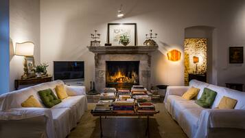 Una sala de estar con dos sofás blancos, una chimenea y una mesa con libros.