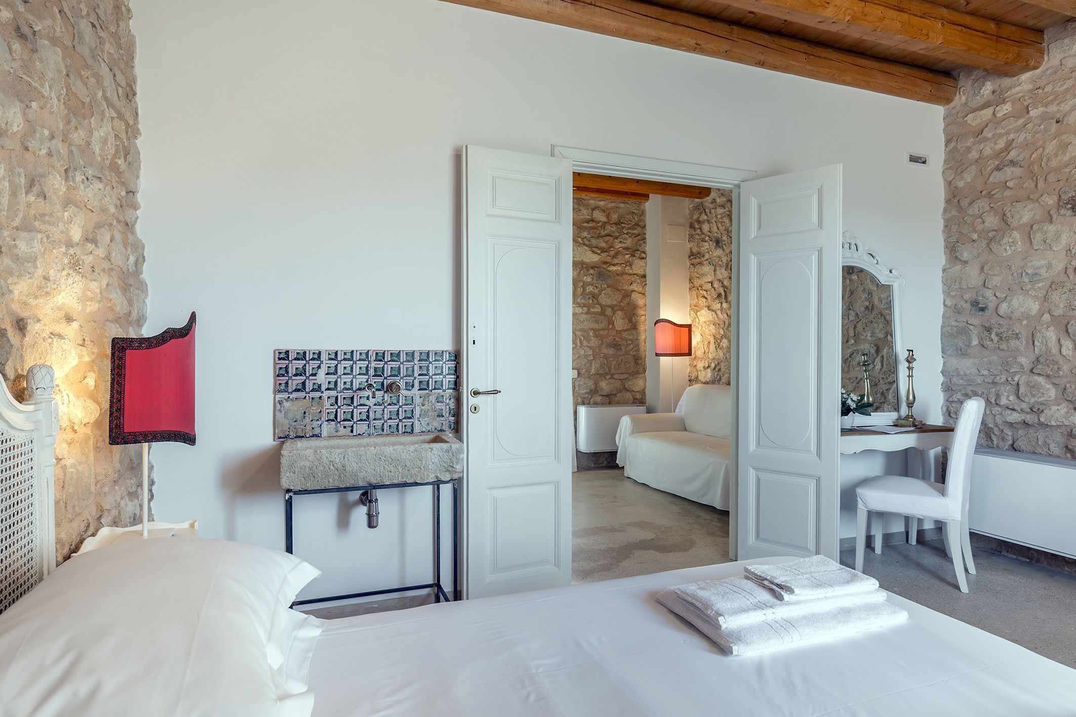 A bedroom with a bed, a desk, a chair, and a bathroom.