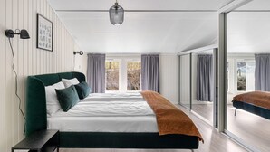Un dormitorio moderno con una cama grande, una mesita de noche, una lámpara colgante y vistas a través de un ventanal.