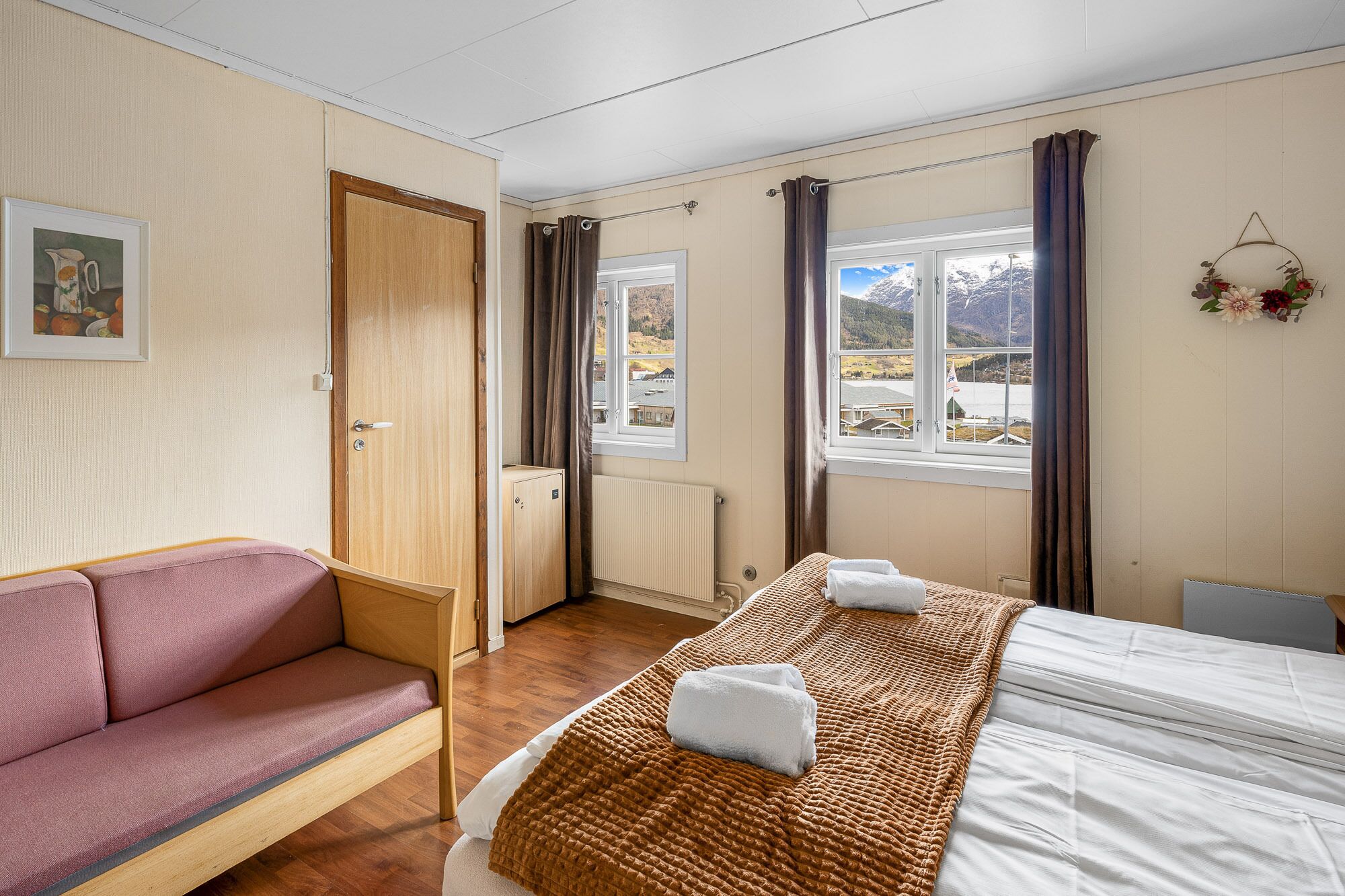 Una habitación de hotel con cama, sofá, ventana y vistas a las montañas, además de un radiador.