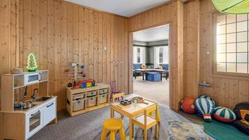 Children can play and learn in this spacious room with a table, chairs, toys, and a kitchenette.
