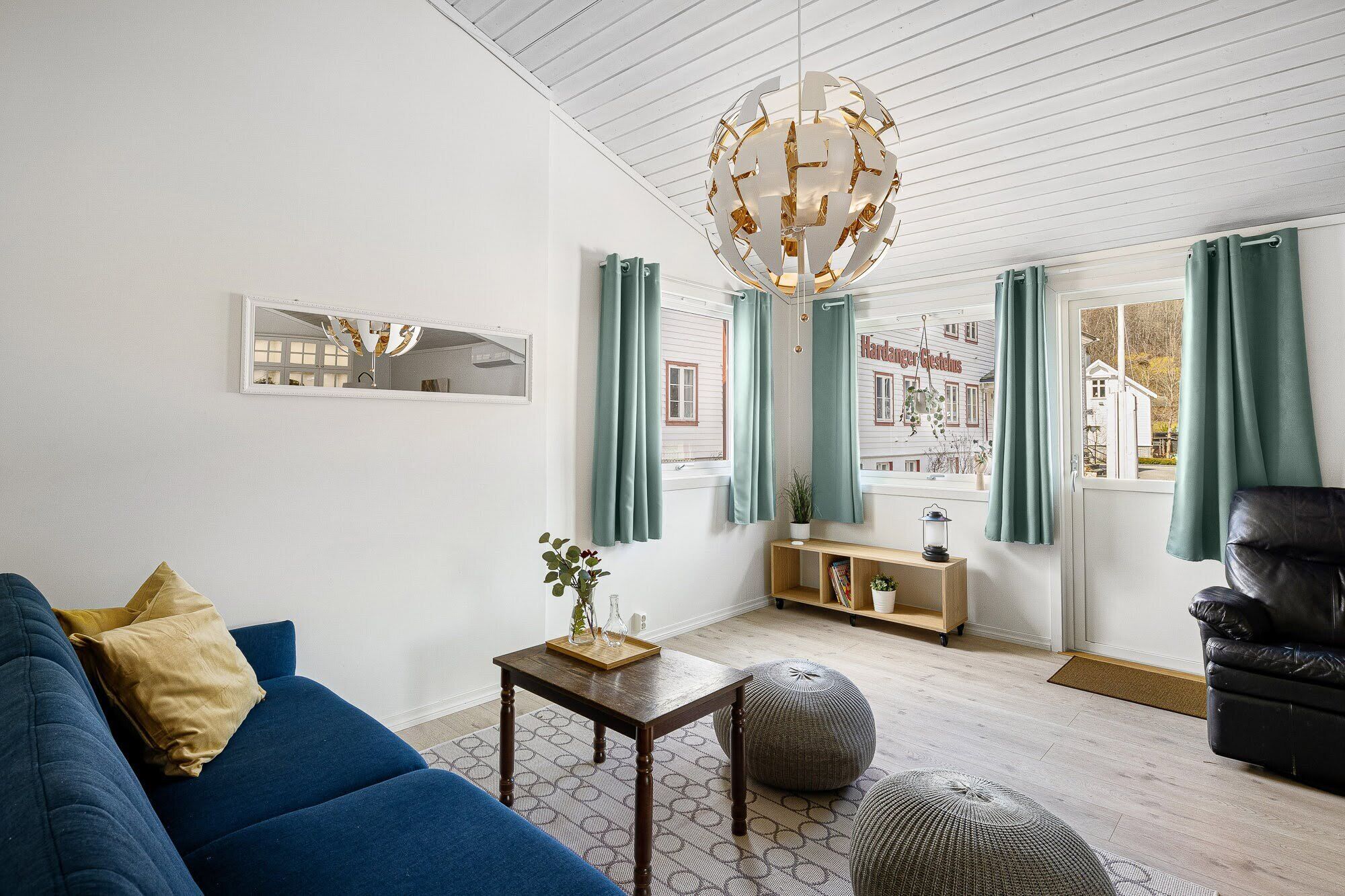 Een moderne woonkamer met een blauwe bank, een houten salontafel en een bijzondere bolvormige lamp.