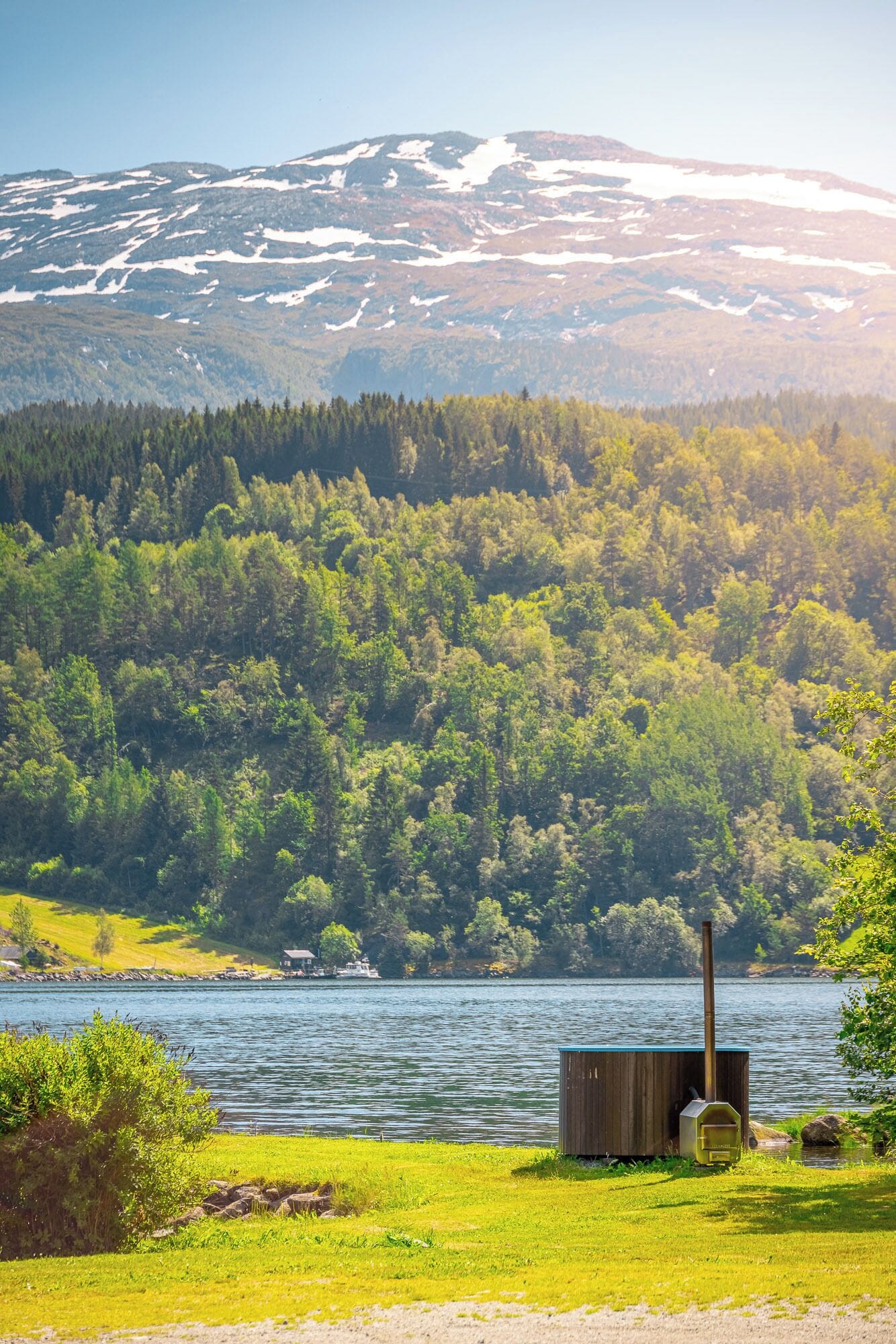 Ein Seehaus mit Blick auf einen bewaldeten Gebirgszug.
