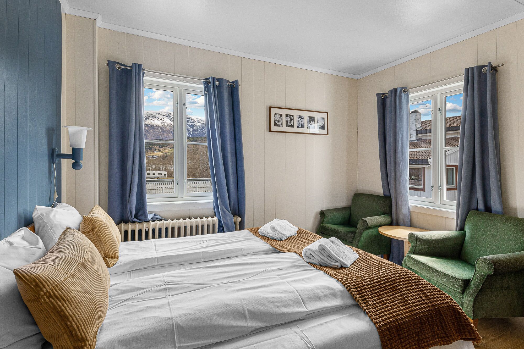 Ein Hotelzimmer mit einem Bett, zwei Stühlen, einem kleinen Tisch und einem Fenster mit Vorhängen.