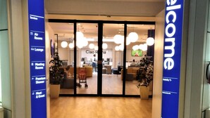 A hotel entrance with a blue sign reading "Welcome" and "Air Rooms & Lounge". - Air Rooms Rome Airport by HelloSky (Fiumicino)
