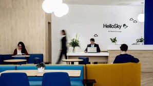 A modern reception area with a wooden wall, a reception desk, and seating areas with blue and yellow chairs. - Air Rooms Rome Airport by HelloSky (Fiumicino)