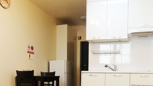 A spacious kitchen with white cabinets, a refrigerator, and a dining area with a table and chairs. - Busan Haeundae Travel Pension (Busan)
