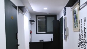 A hallway with a wooden floor, a black refrigerator, a small sink, and a calendar on the wall. - Busan Haeundae Travel Pension (Busan)