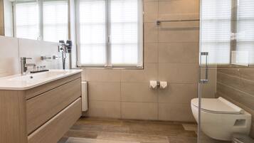 Une salle de bain moderne avec un meuble-lavabo en bois, des toilettes et une douche à parois de verre.